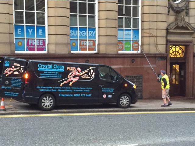 Side of Crystal Clean van and a window being cleaned